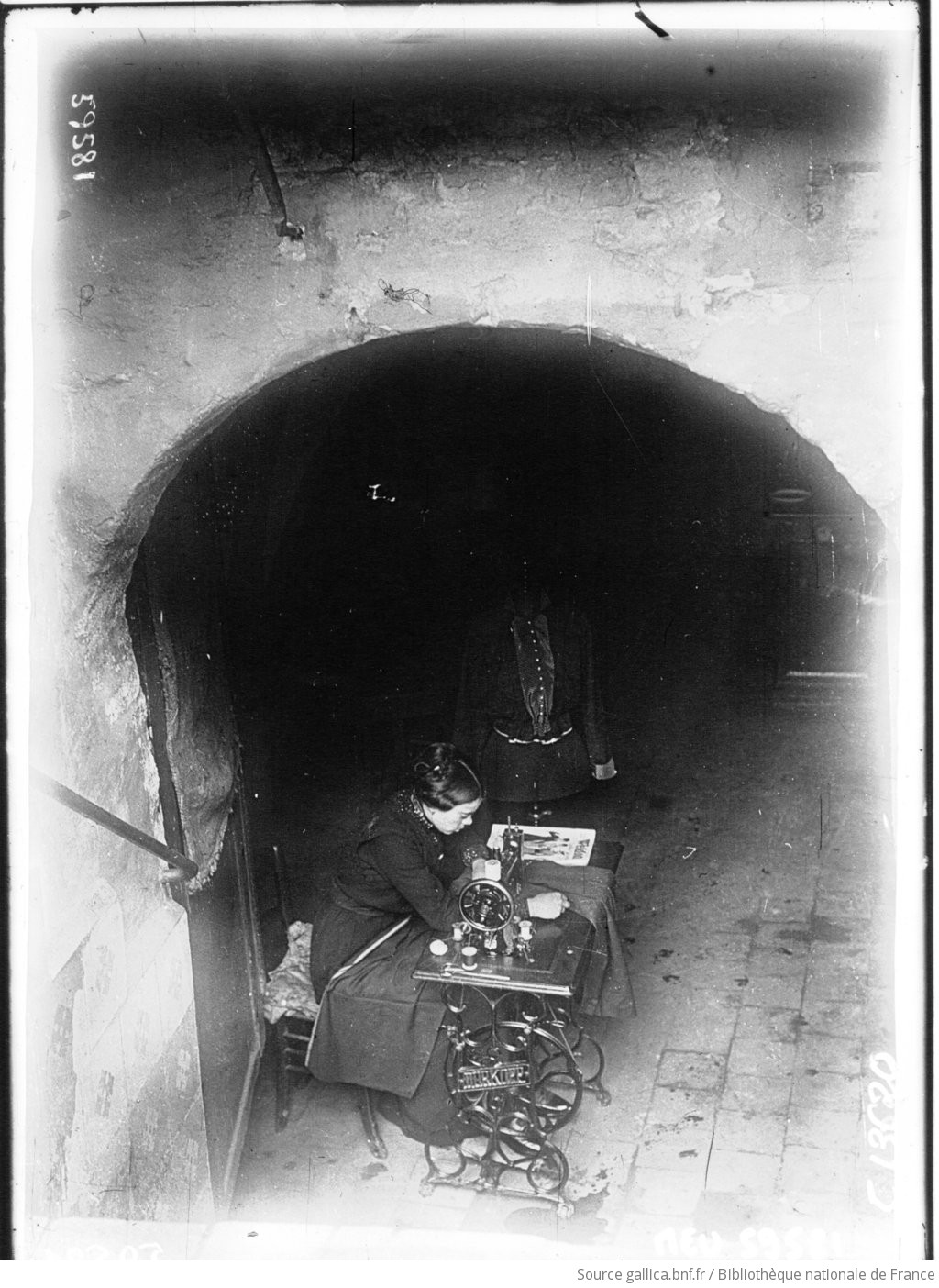 Une couturière travaille dans une cave qui lui sert d'habitation, à Reims : [photographie de presse] / Agence Meurisse - 1